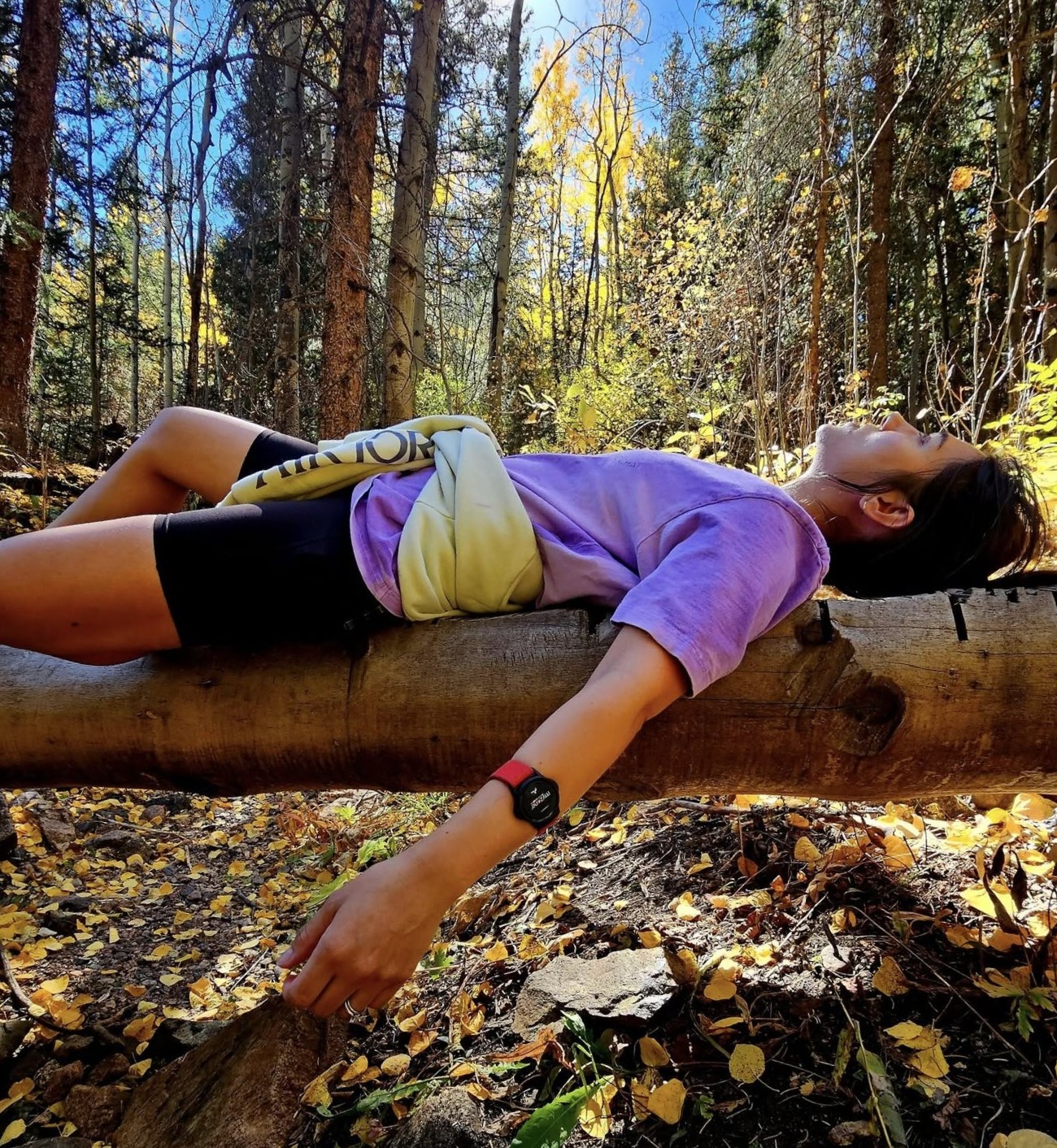 Me, Jennifer, lying on a log surrounded by aspen trees during fall in Colorado